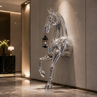 Mirror polished stainless steel horse wall sculpture with lantern displayed in a luxury hotel lobby interior.