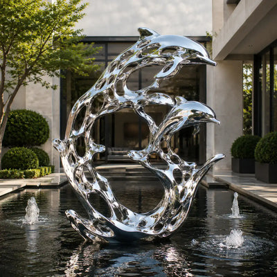 Large stainless steel dolphin sculpture with mirror polished finish installed in a luxury outdoor water feature.